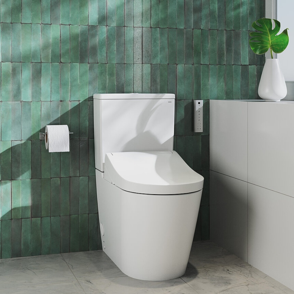 Lifestyle image of the TOTO Washlet RG Lite Rimless Close Coupled Toilet installed in a bathroom next to a toilet roll holder and bathroom table
